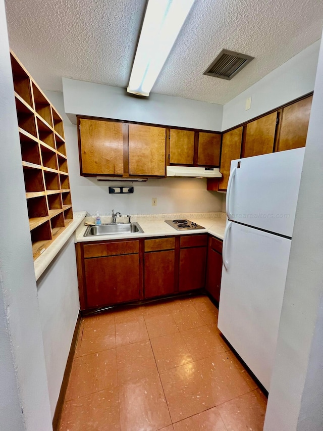 9670 Smith Lake Rd, Jasper, AL 35504 - kitchen featuring freestanding refrigerator, under cabinet range hood, a textured ceiling, stainless steel cooktop, and light countertops