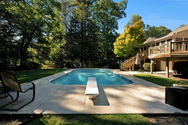 outdoor pool featuring stairs, a deck, a patio area, and a diving board