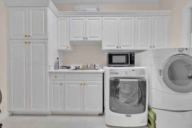 washroom with a sink, cabinet space, independent washer and dryer, and light tile patterned floors