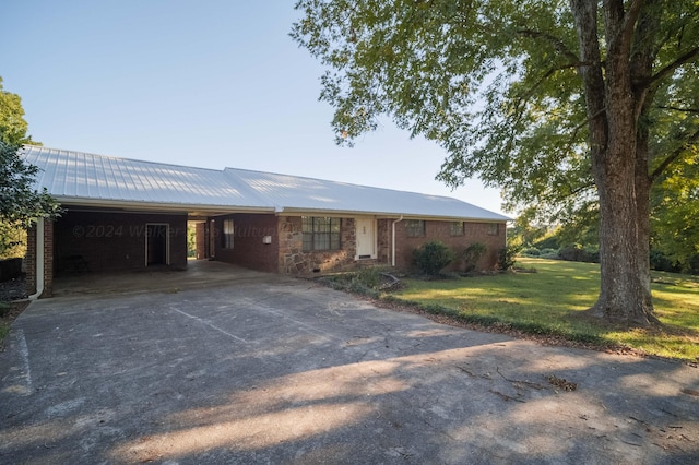 single story home with metal roof, a front yard, brick siding, driveway, and a carport
