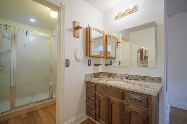 full bath with a shower stall, baseboards, ornamental molding, wood finished floors, and vanity
