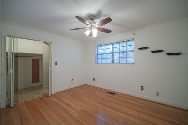 unfurnished bedroom with baseboards, visible vents, crown molding, and light wood-style flooring