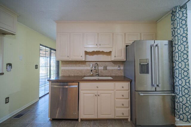 kitchen with a sink, dark countertops, tasteful backsplash, and appliances with stainless steel finishes