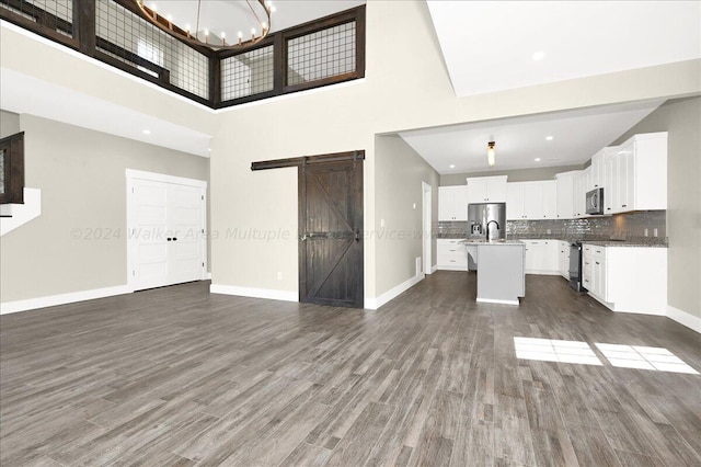 3195 County Road 51, Bremen, AL 35033 - unfurnished living room featuring a sink, dark wood-type flooring, a barn door, and baseboards