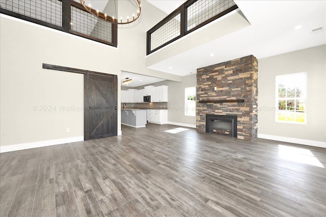 3195 County Road 51, Bremen, AL 35033 - unfurnished living room with a chandelier, a barn door, a large fireplace, baseboards, and dark wood-type flooring
