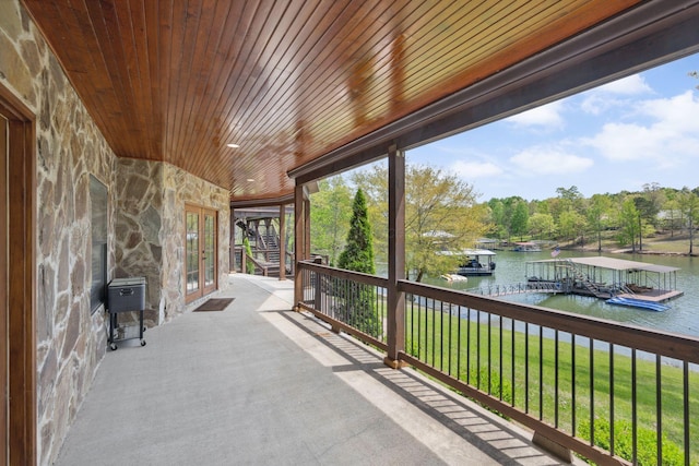view of patio with a dock, a water view, and french doors