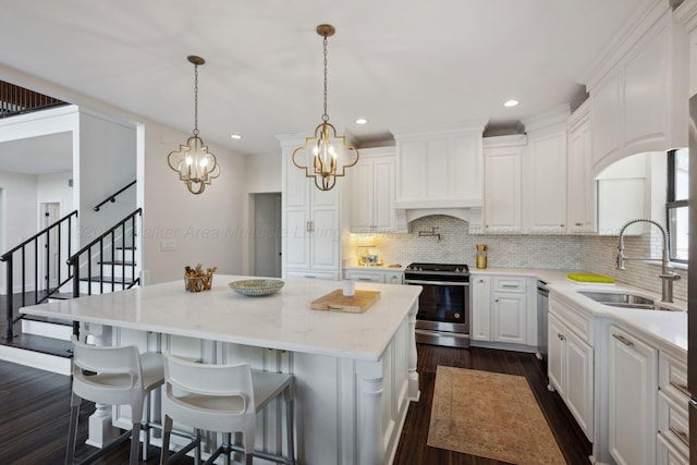 kitchen featuring tasteful backsplash, white cabinets, a sink, appliances with stainless steel finishes, and a kitchen island