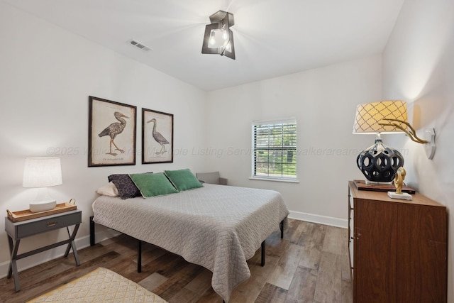 bedroom with wood finished floors, visible vents, a ceiling fan, and baseboards