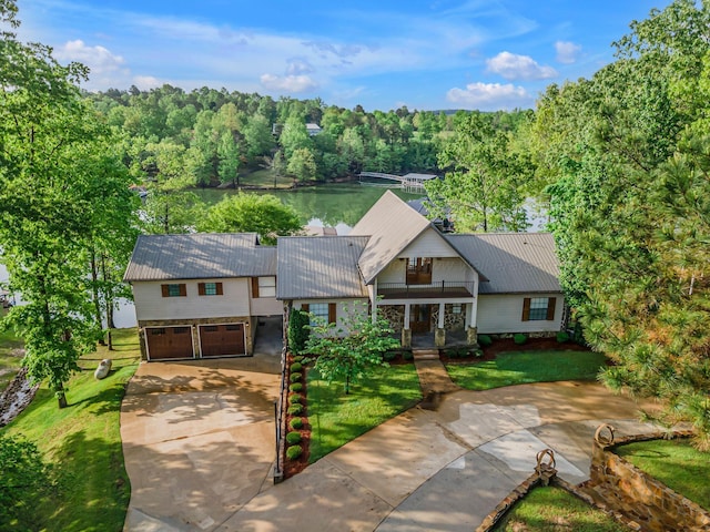 view of front of property featuring a water view, metal roof, driveway, a front yard, and an attached garage