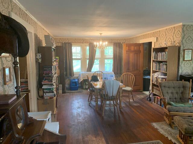 dining space featuring a chandelier, dark wood-type flooring, and ornamental molding