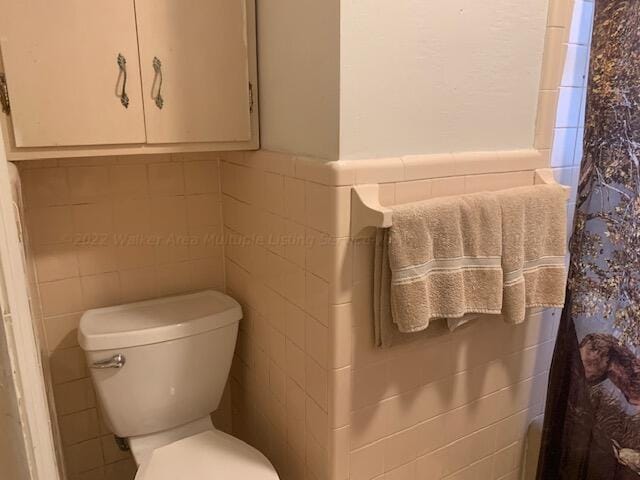 bathroom with toilet and tile walls