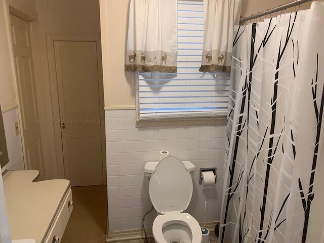 bathroom with vanity, tile walls, and toilet