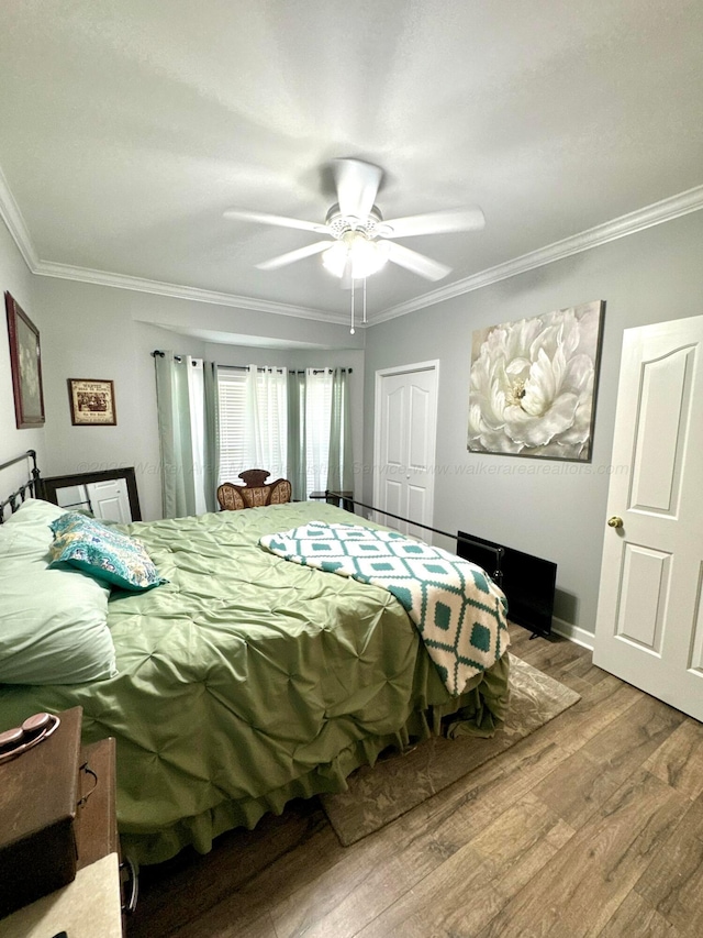 bedroom with wood finished floors, a closet, and ornamental molding