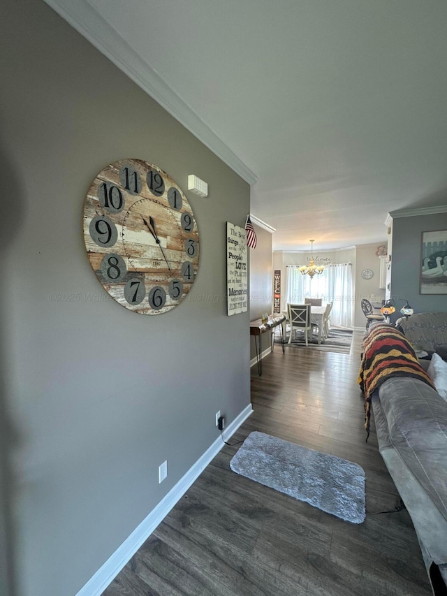 living area featuring wood finished floors, a notable chandelier, baseboards, and ornamental molding