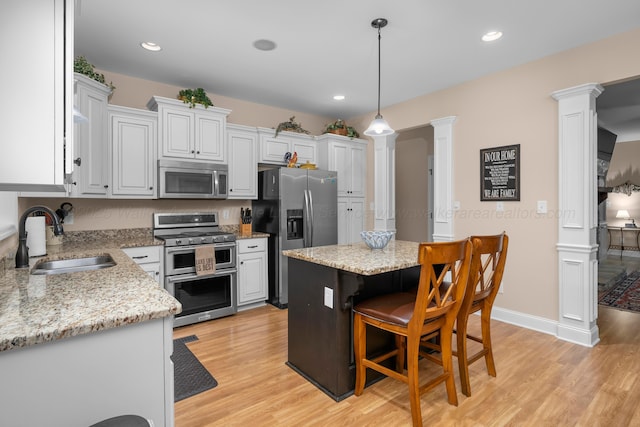 1528 Sipsey Rd, Double Springs, AL 35553 - kitchen featuring appliances with stainless steel finishes, decorative columns, light wood-style floors, a kitchen bar, and decorative light fixtures