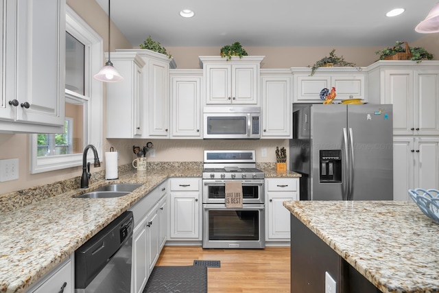 1528 Sipsey Rd, Double Springs, AL 35553 - kitchen with appliances with stainless steel finishes, white cabinetry, pendant lighting, light wood-style flooring, and light stone counters