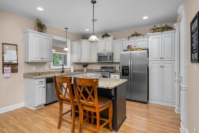 1528 Sipsey Rd, Double Springs, AL 35553 - kitchen with appliances with stainless steel finishes, light wood-type flooring, a kitchen island, a kitchen bar, and white cabinets