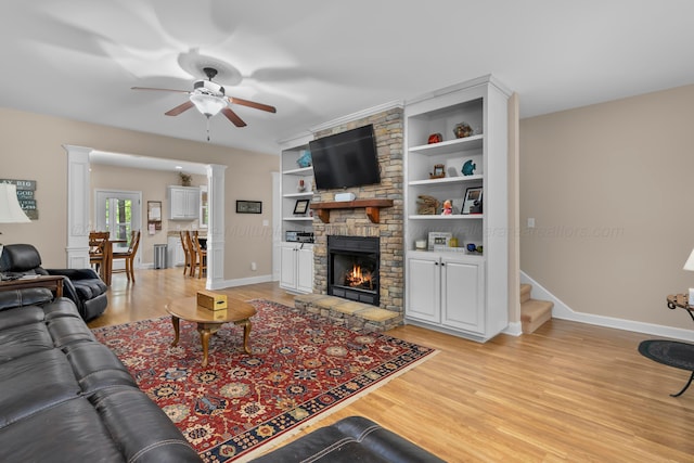 1528 Sipsey Rd, Double Springs, AL 35553 - living area with ceiling fan, light wood-style floors, a stone fireplace, ornate columns, and stairs