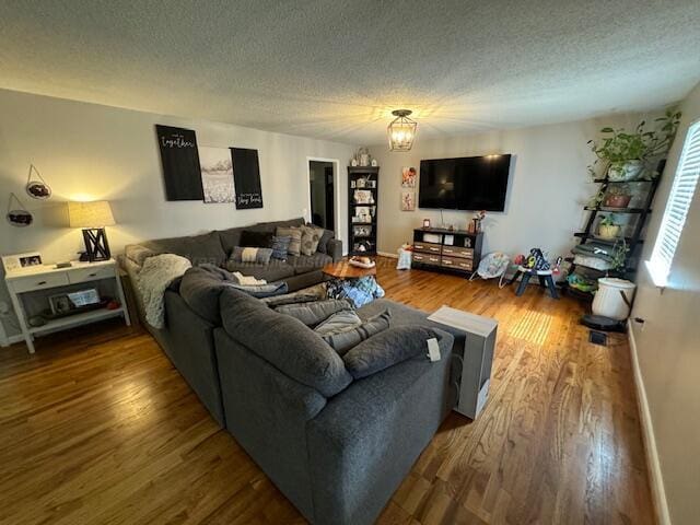 living room with hardwood / wood-style floors, a notable chandelier, and a textured ceiling