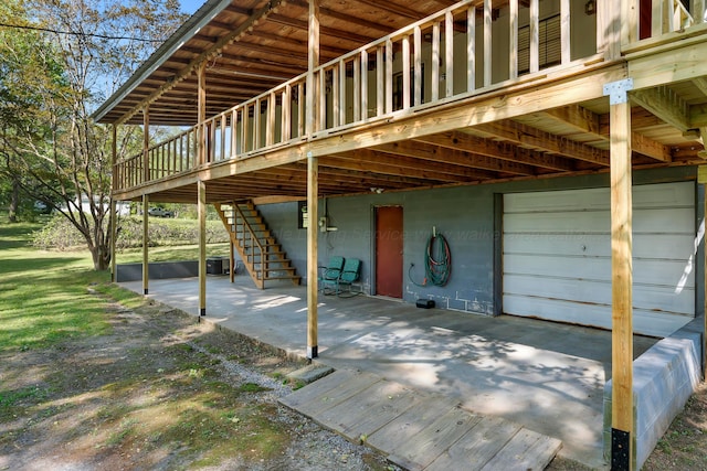 view of patio with an attached garage, a wooden deck, and stairs