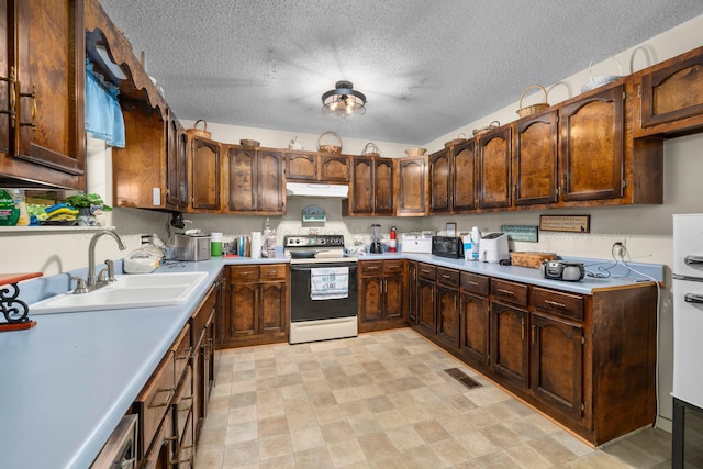 kitchen with a sink, visible vents, electric range oven, light countertops, and under cabinet range hood