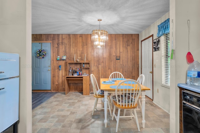 dining area with a notable chandelier, visible vents, and wooden walls