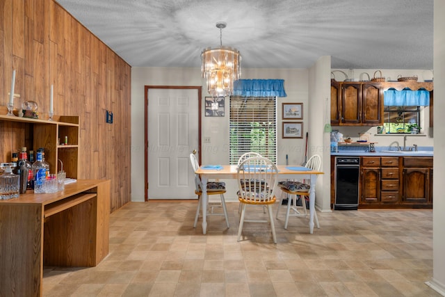 dining space with a chandelier, a textured ceiling, and wood walls