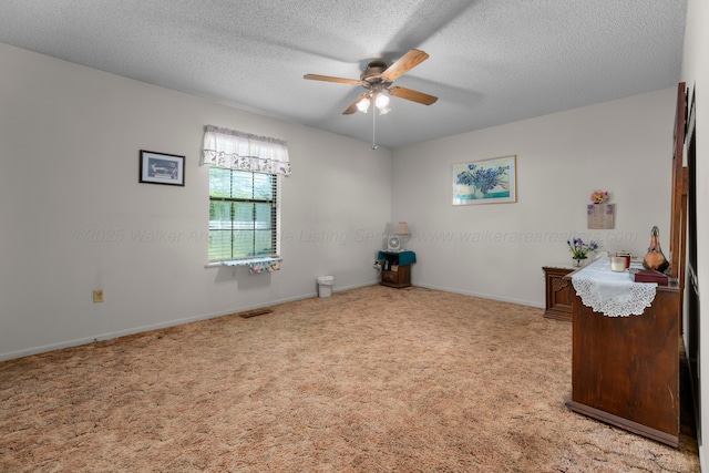 spare room featuring visible vents, baseboards, a textured ceiling, light colored carpet, and ceiling fan