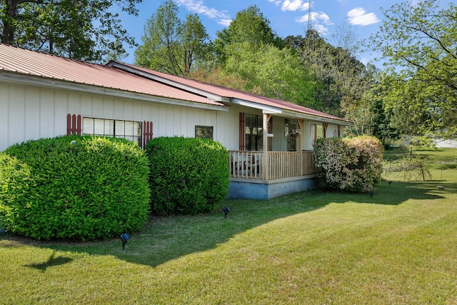 view of side of home featuring a yard, metal roof, and covered porch