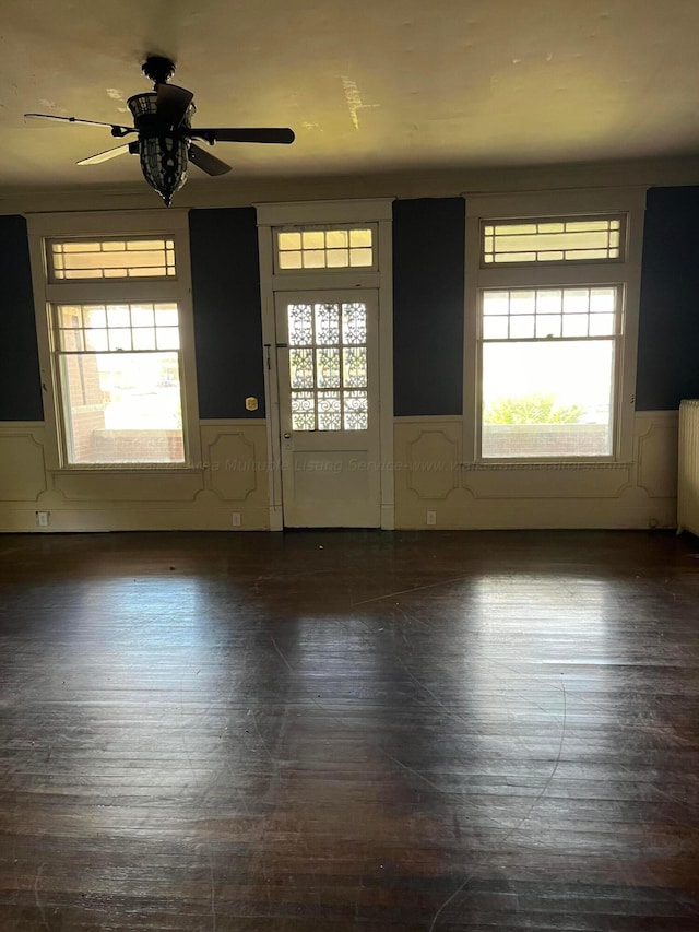 foyer entrance featuring radiator heating unit, a wainscoted wall, and a ceiling fan