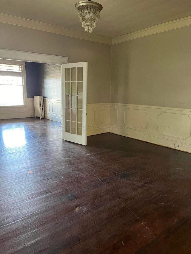 unfurnished room featuring dark wood-type flooring, ornamental molding, wainscoting, and radiator