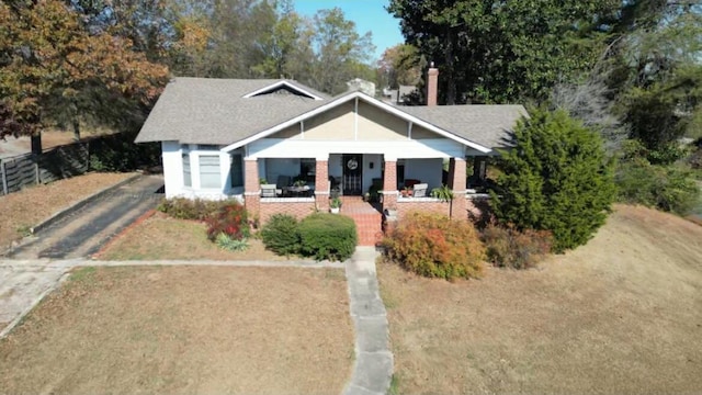 bungalow-style house with covered porch, driveway, and fence