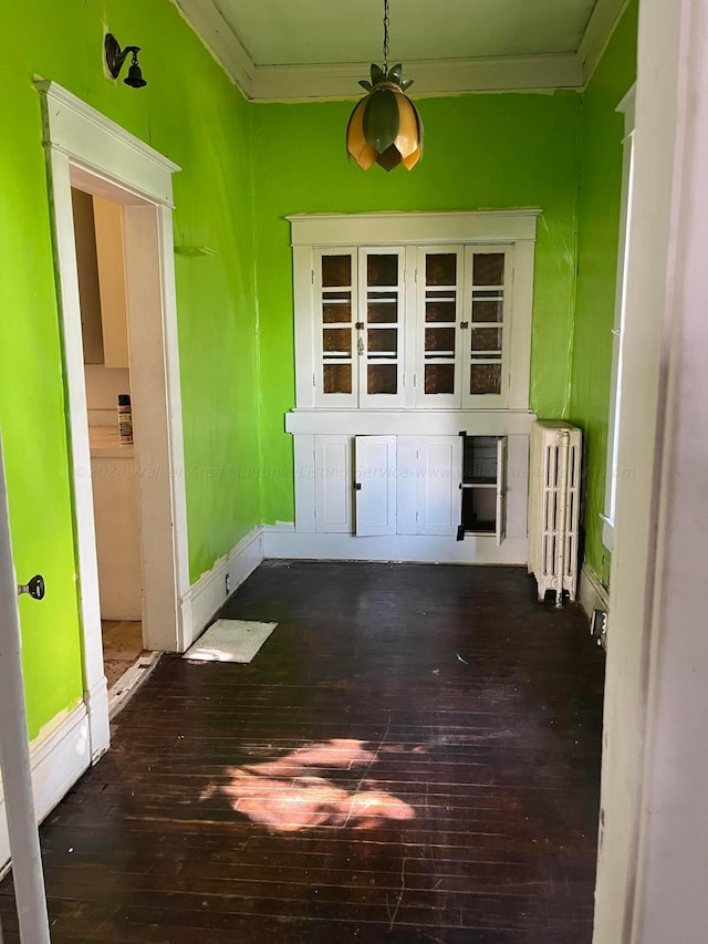 interior space with baseboards, radiator heating unit, crown molding, and wood-type flooring