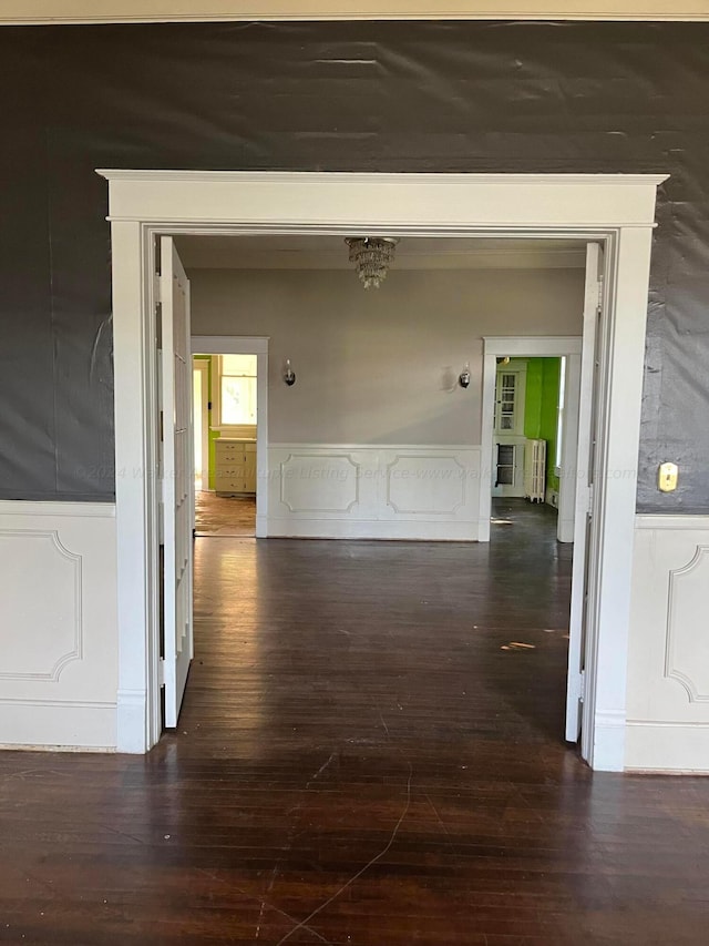 corridor with wainscoting, a decorative wall, and hardwood / wood-style floors