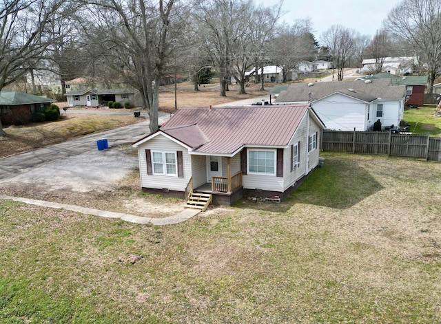 rear view of house featuring metal roof, fence, a yard, crawl space, and a residential view