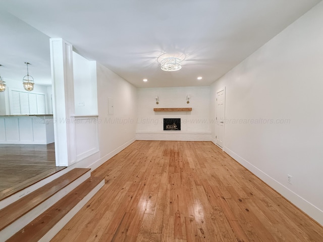2301 E 20th Ave, Jasper, AL 35501 - unfurnished living room featuring a chandelier, hardwood / wood-style floors, a fireplace with raised hearth, baseboards, and recessed lighting