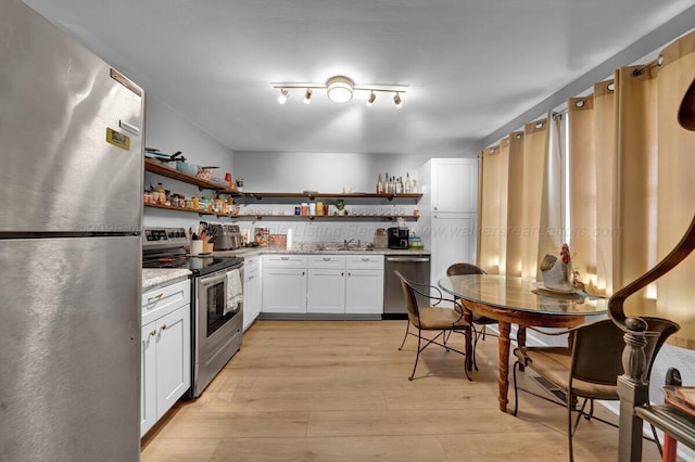 809 W 15th St, Jasper, AL 35501 - kitchen with stainless steel appliances, open shelves, light wood-style floors, and white cabinets