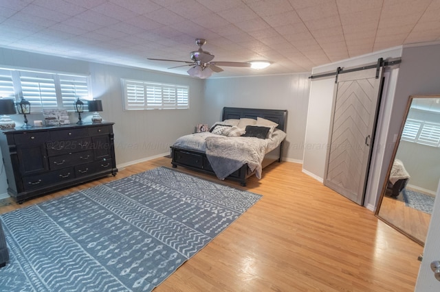 1602 27th St, Haleyville, AL 35565 - bedroom featuring a barn door, multiple windows, wood finished floors, ornamental molding, and a ceiling fan