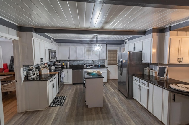 1602 27th St, Haleyville, AL 35565 - kitchen featuring stainless steel appliances, dark countertops, dark wood-style flooring, decorative backsplash, and a center island