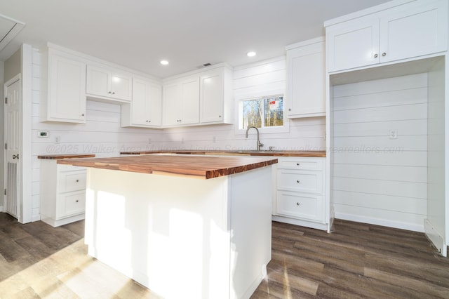 204 NW Piney Dr, Cullman, AL 35055 - kitchen with butcher block countertops, dark wood-style flooring, white cabinets, a kitchen island, and a sink