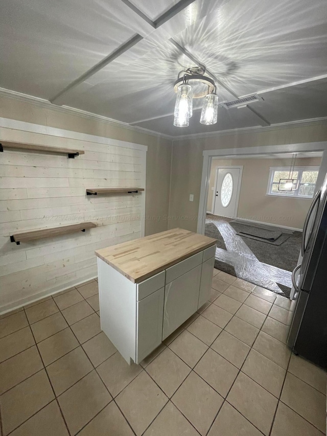 kitchen featuring crown molding, open shelves, butcher block countertops, light tile patterned flooring, and freestanding refrigerator
