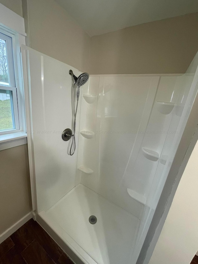 bathroom featuring a shower stall, baseboards, and wood finished floors