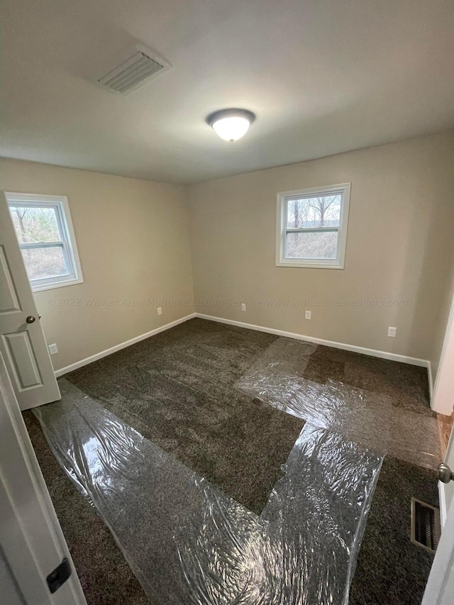 empty room with baseboards, a wealth of natural light, and visible vents