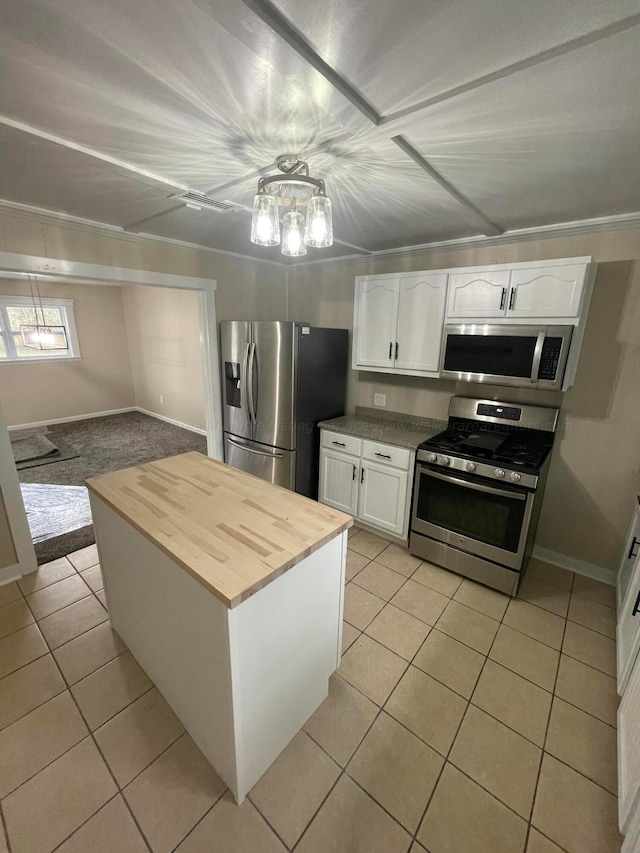 kitchen featuring a kitchen island, butcher block counters, light tile patterned floors, stainless steel appliances, and white cabinets