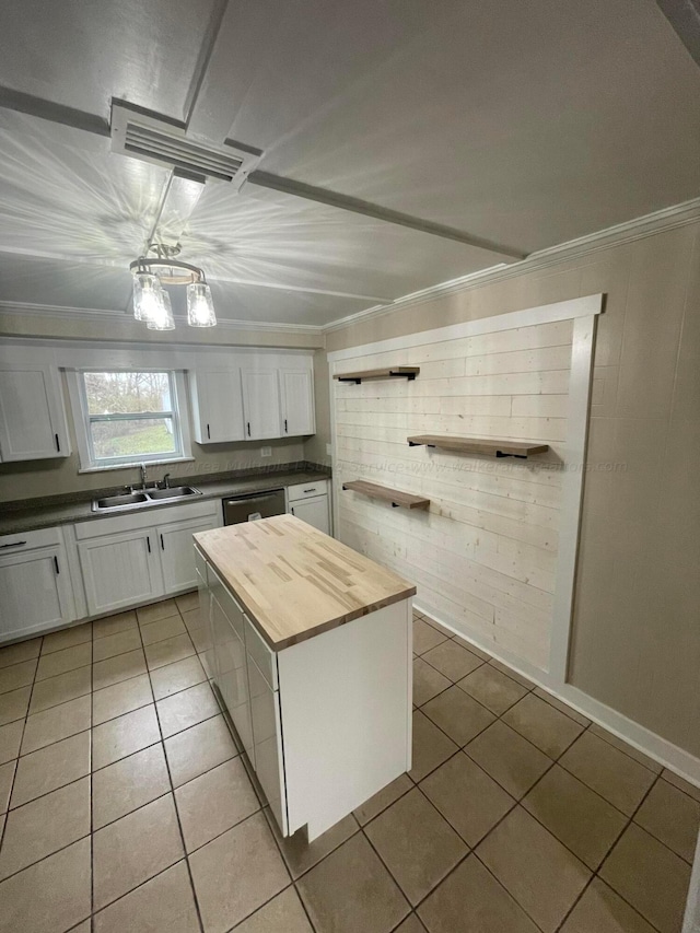 kitchen with white cabinetry, wooden counters, light tile patterned floors, and dishwashing machine