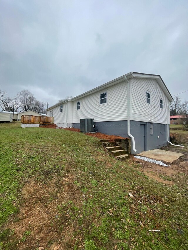 rear view of property with central air condition unit and a yard