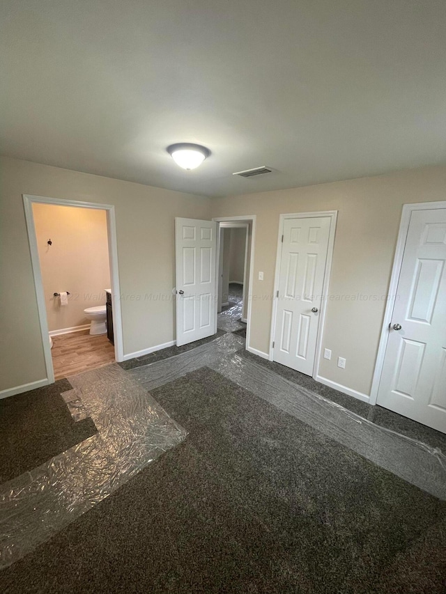 unfurnished bedroom featuring baseboards, visible vents, and ensuite bath