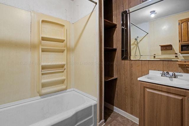 bathroom featuring shower / bathing tub combination, vanity, and wooden walls