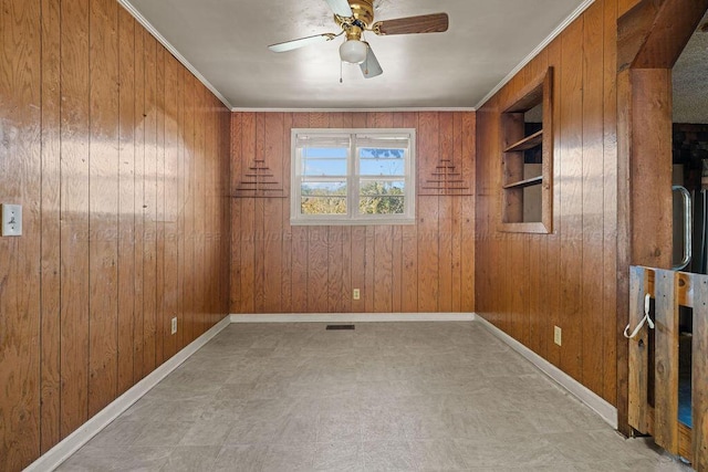 empty room featuring ceiling fan, wood walls, built in features, and ornamental molding