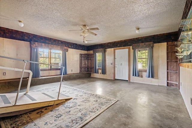 interior space with ceiling fan, a textured ceiling, a wealth of natural light, and concrete floors